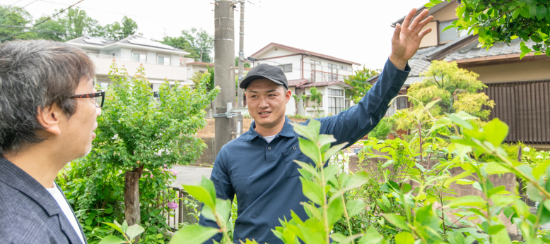 雑草の調査をしてお客様とお話をしている男性スタッフ